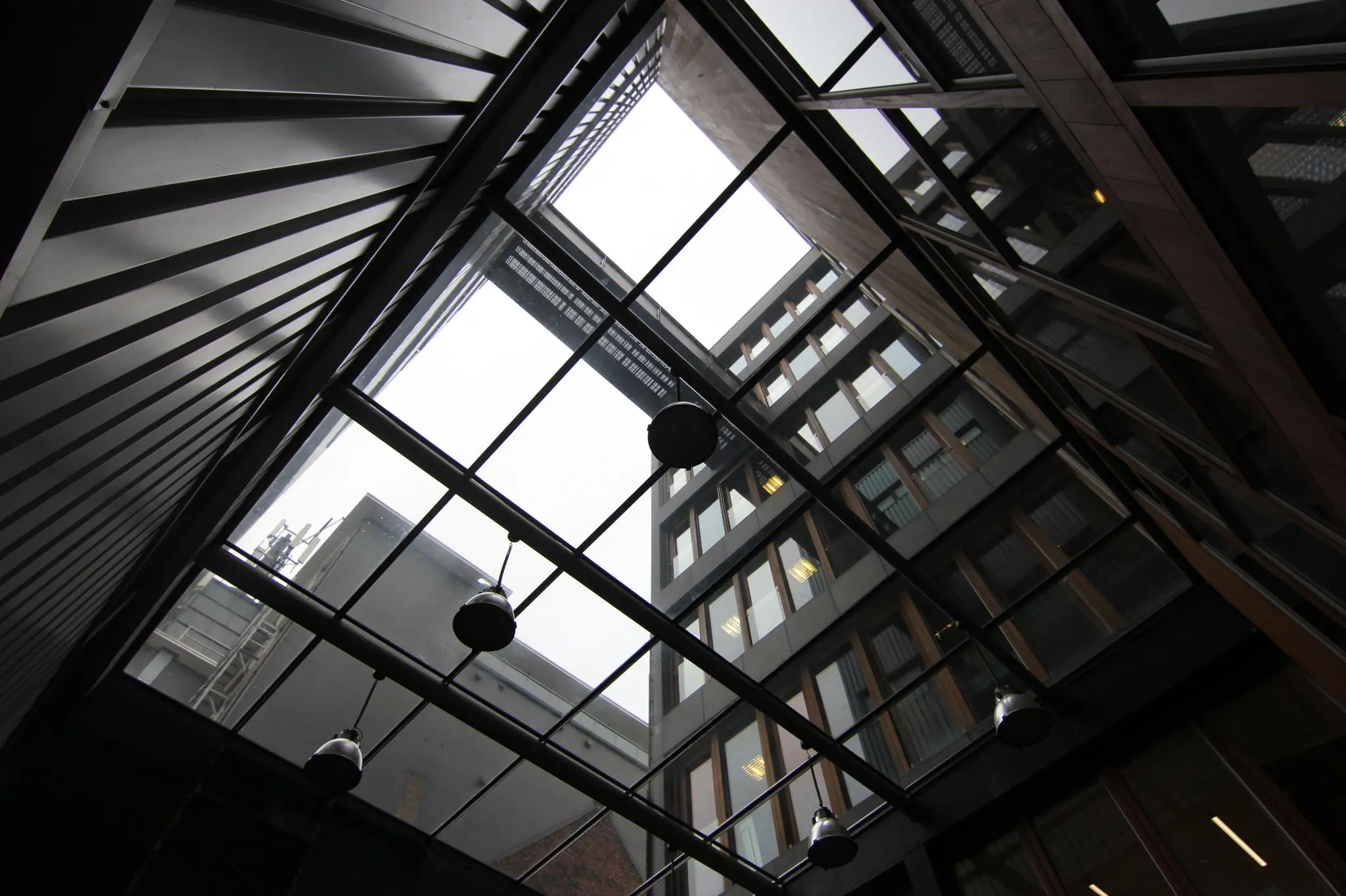 Blik omhoog vanuit een overdekte binnenplaats naar de gevels van moderne gebouwen aan de De Ruijterkade.